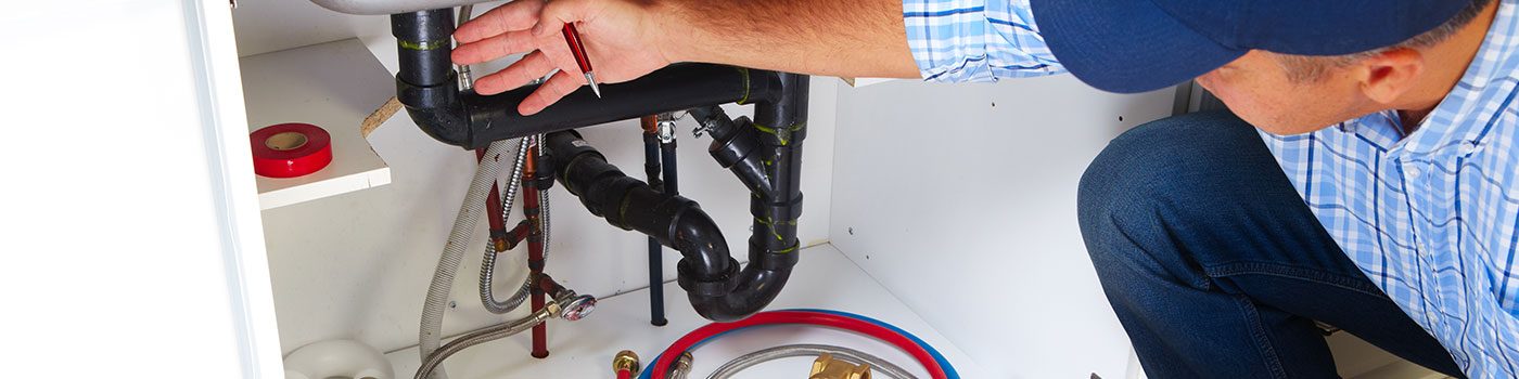Plombier réparant une canalisation sous un évier