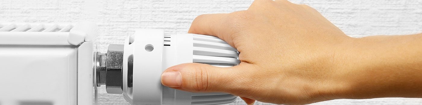 Main réglant le robinet thermostatique d'un radiateur